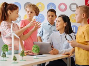 Smart schoolchildren sharing their ecology project idea with teacher